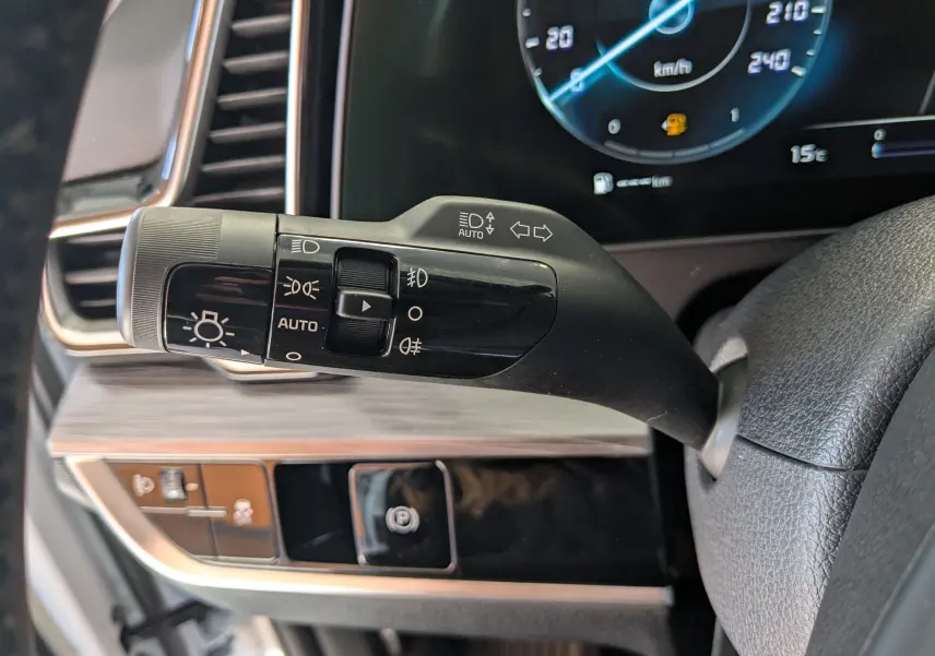 Gros plan sur la commande des phares et clignotants du tableau de bord du Kia Sportage blanc MY25.