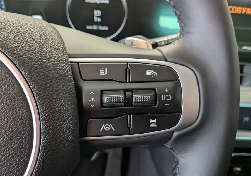 Gros plan sur les commandes de régulateur de vitesse au volant cuir noir du Kia Sportage blanc MY25.