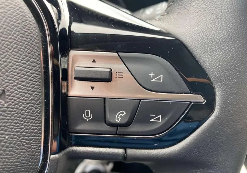 Gros plan sur les commandes noires du volant de la Peugeot 308 2023, finition Allure Pack, intérieur noir.