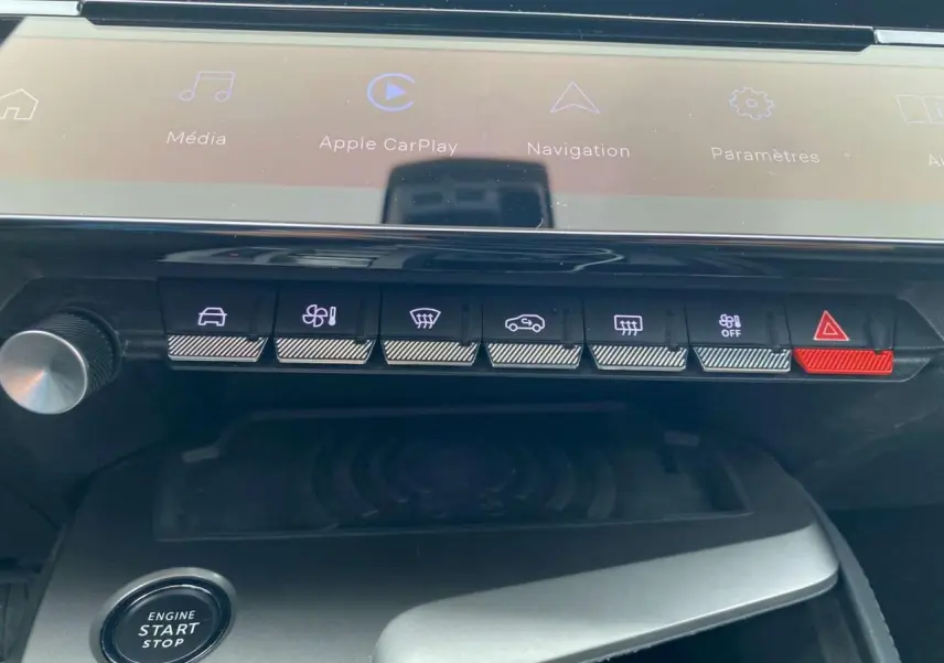 Gros plan sur la console centrale de la Peugeot 308 2023 avec commandes tactiles et chargeur induction visible.