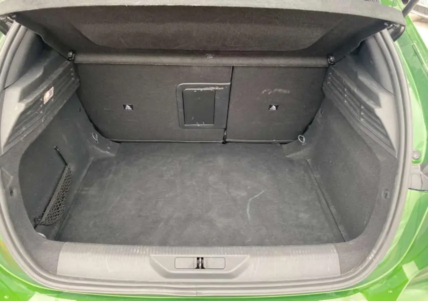 Coffre ouvert vu de l'arrière d'une Peugeot 308 2023 vert olivine, montrant un espace de chargement propre et spacieux.