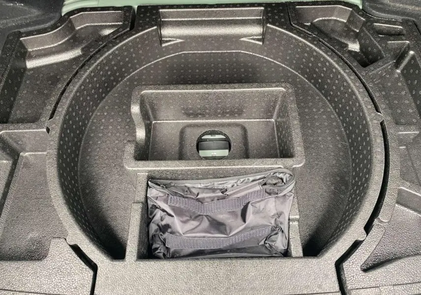 Rangement de coffre en mousse noire avec sacoche, partie arrière d'une Peugeot 308 Vert Olivine 2023 visible au fond.