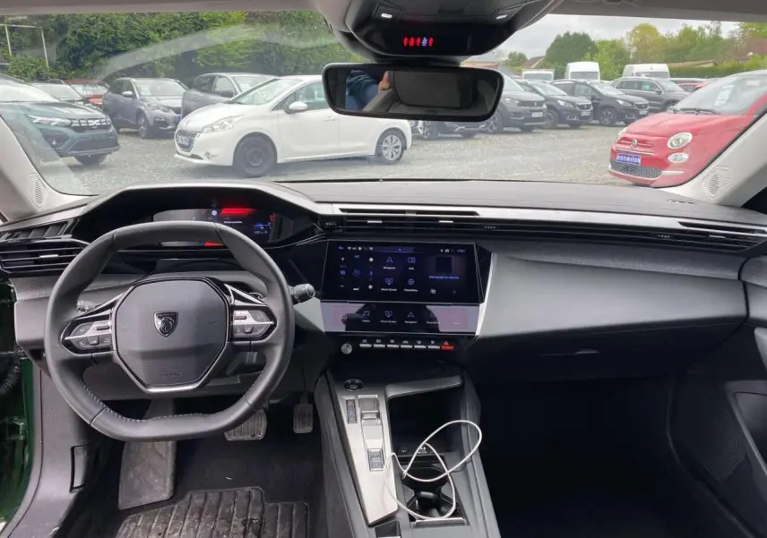 Intérieur de la Peugeot 308 2023 vue de face, tableau de bord noir avec écran tactile central et volant compact.