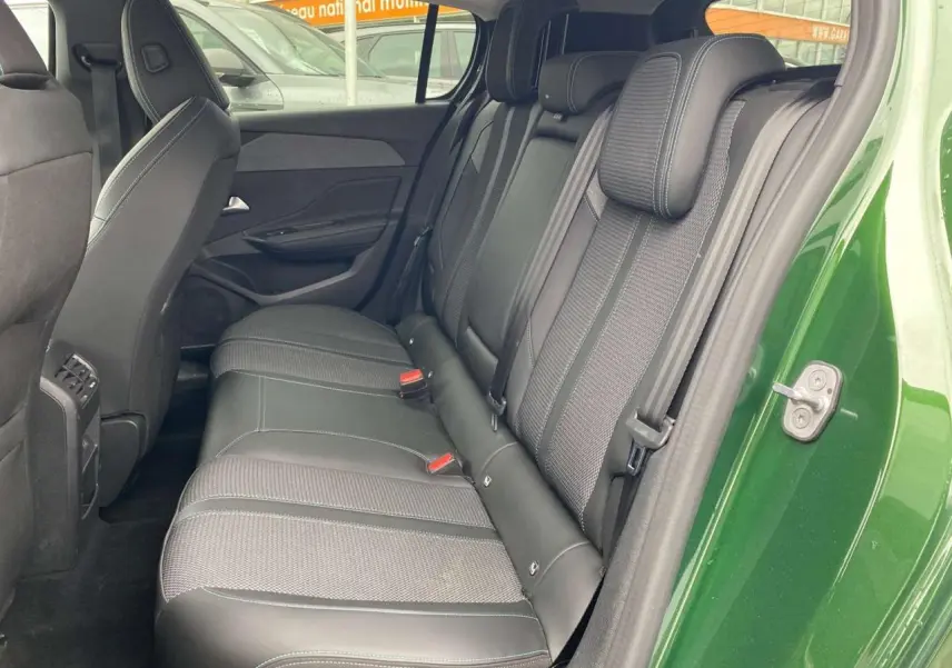 Vue côté gauche de la banquette arrière en cuir noir de la Peugeot 308 2023 vert olivine avec porte ouverte.