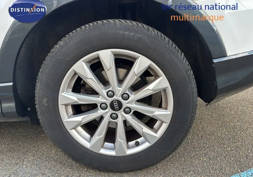 Gros plan sur la roue avant gauche de l'Audi Q3 Sportback blanc avec jante alliage 18 pouces au design moderne.