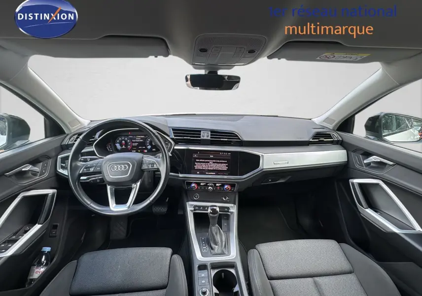 Vue intérieure avant de l'Audi Q3 Sportback 2021, tableau de bord moderne avec écran tactile et volant multifonction noir.