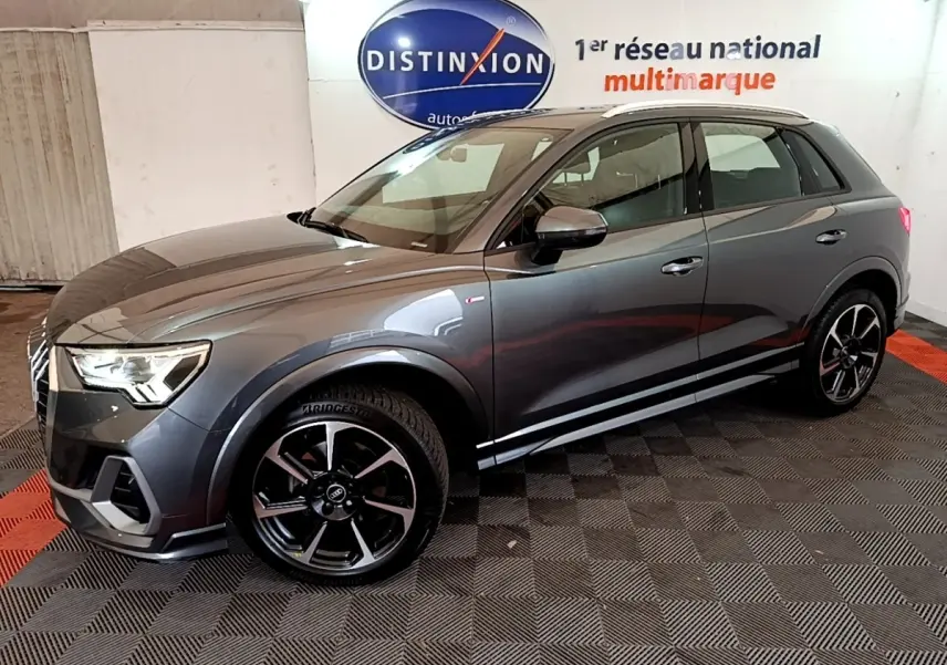 Audi Q3 35 TFSI S Line gris foncé, vue 3/4 avant droit, avec jantes noires et détails S Line visibles.