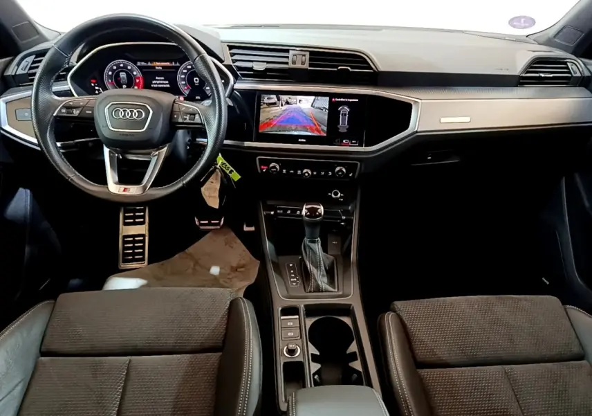 Vue intérieure avant de l'Audi Q3 35 TFSI S Line 2022, tableau de bord moderne avec écran tactile et volant cuir multifonctions.