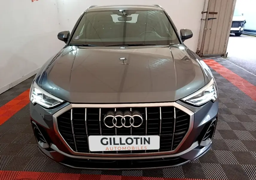 Vue avant d'un Audi Q3 gris foncé 35 TFSI S Line 2022 avec calandre large et phares LED allumés.