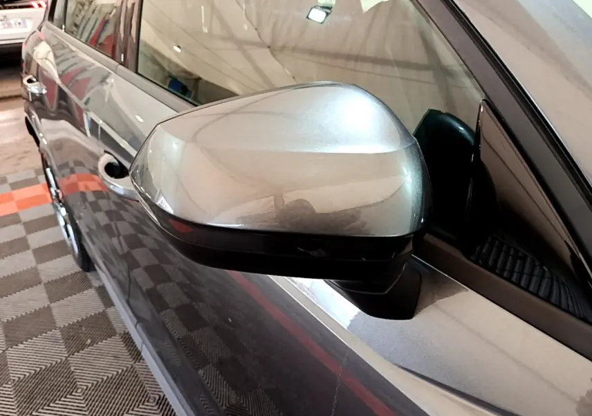 Rétroviseur côté gauche gris foncé d’un Audi Q3 35 TFSI S Line 2022, vue rapprochée en intérieur de garage.