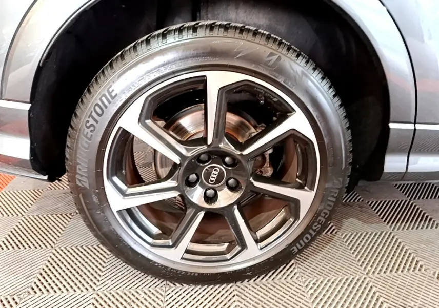 Gros plan sur la roue avant gauche de l'Audi Q3 gris foncé, avec jante alliage cinq branches et pneu Bridgestone.