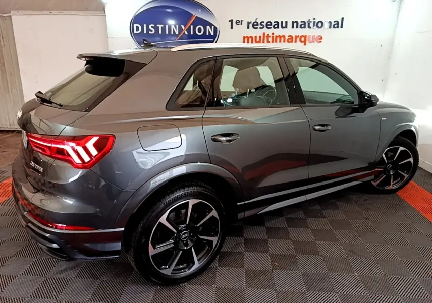 Audi Q3 35 TFSI S Line gris foncé vue 3/4 arrière droit, feux LED allumés et jantes noires distinctives.