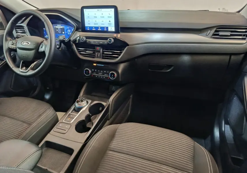 Vue intérieure avant du Ford Kuga 2023 gris foncé, avec tableau de bord digital et écran tactile central.