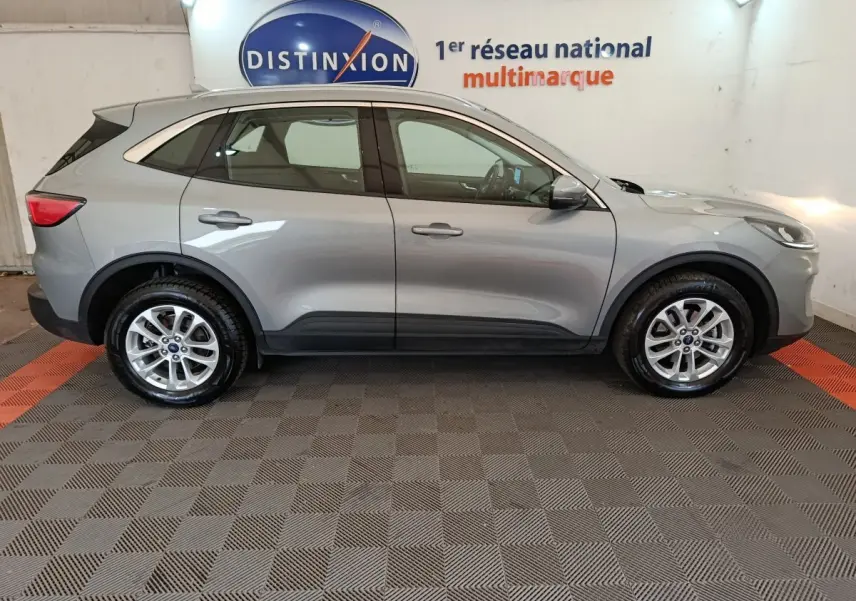 Vue de profil côté gauche d'un Ford Kuga gris foncé 2023 avec jantes alliage et barres de toit chromées.