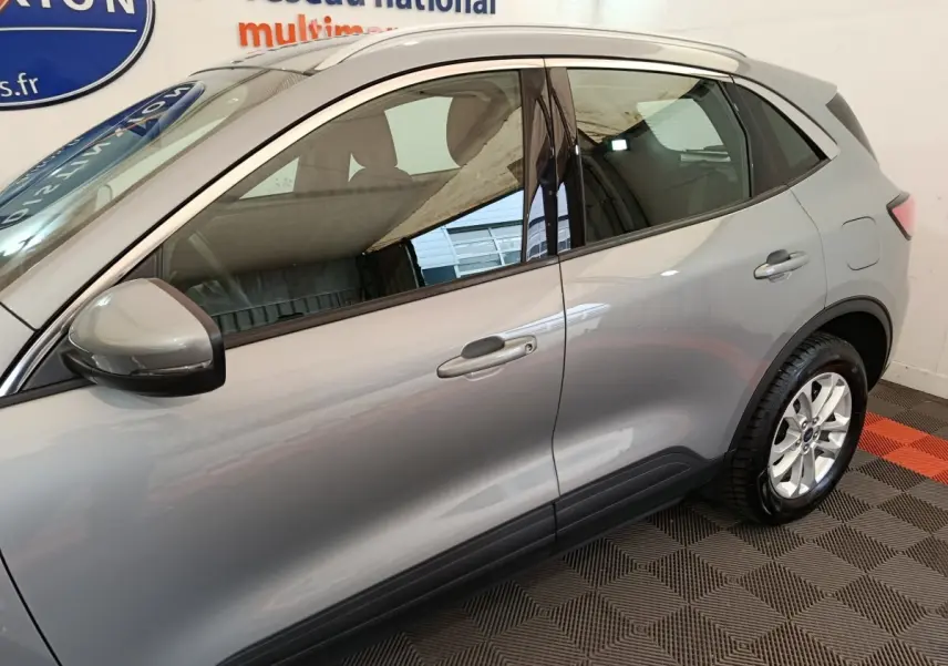 Vue latérale côté gauche d'un Ford Kuga gris foncé 2023 avec rétroviseur et poignées assortis.