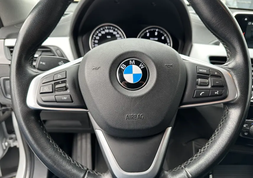 Vue rapprochée du volant noir en cuir avec commandes intégrées du BMW X2 gris diesel 2018 version Lounge.