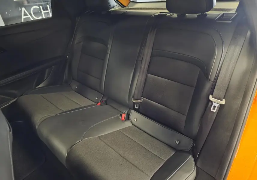 Vue intérieure de la banquette arrière noire en tissu et similicuir du MG4 orange, avec ceintures de sécurité visibles.