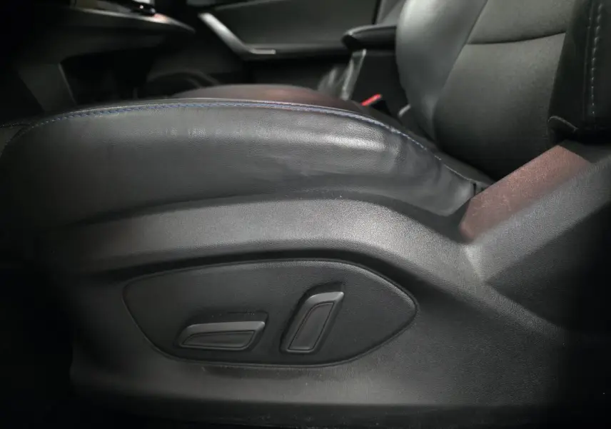 Gros plan sur les commandes électriques du siège conducteur en cuir noir de la MG4 Luxury 2022, intérieur sombre.