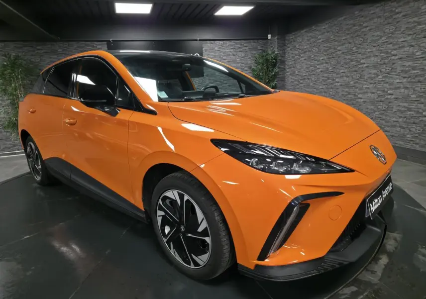 MG4 électrique orange vue 3/4 avant droit avec toit noir contrasté et jantes alliage bi-ton.