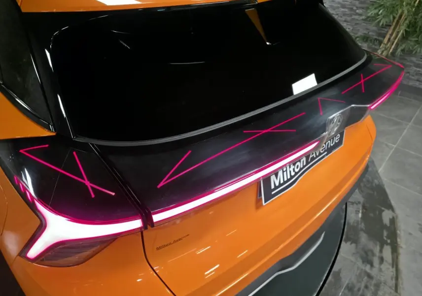 Vue arrière rapprochée du MG4 orange avec feux arrière LED en bandeau lumineux et toit noir contrasté.