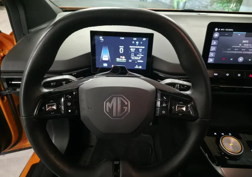 Vue rapprochée du volant cuir noir de la MG4 orange avec tableau de bord numérique et écran tactile central.
