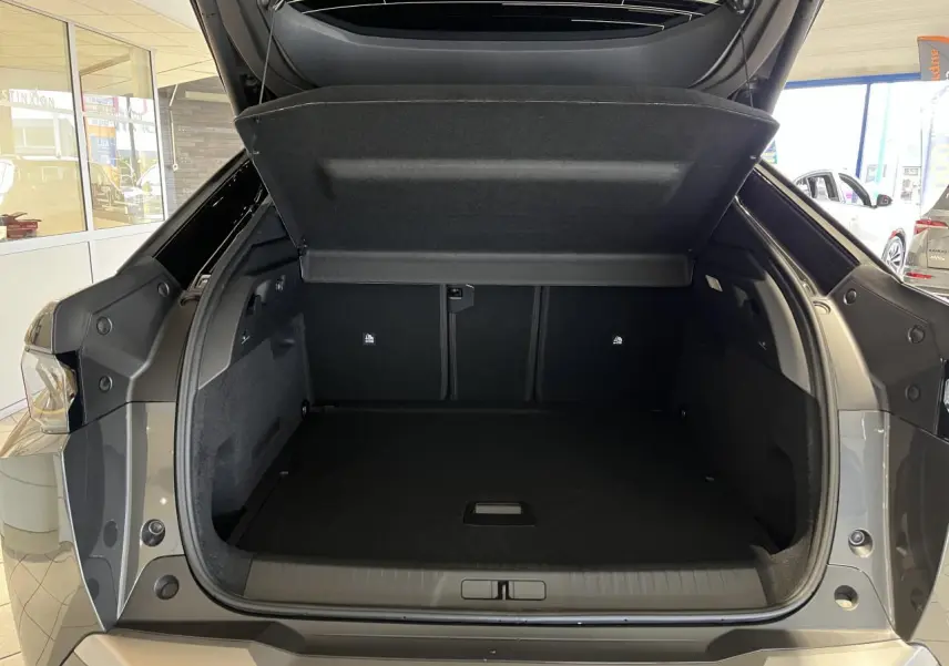 Coffre ouvert vu de l'arrière d'un Peugeot 3008 gris titanium avec intérieur noir dans un showroom.