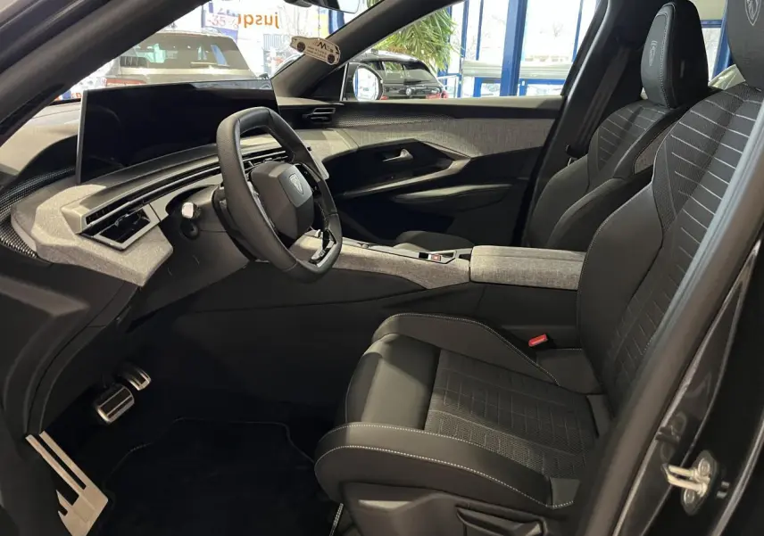 Vue intérieure côté conducteur du Peugeot 3008 gris titanium, avec sièges tissu embossé et volant compact cuir noir laqué.