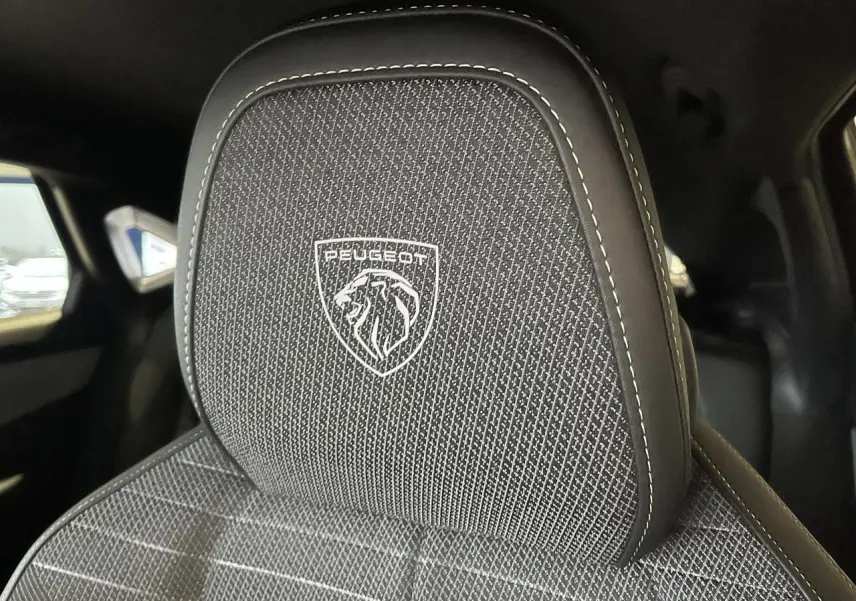 Gros plan sur l'appui-tête avant avec logo Peugeot brodé sur la sellerie tissu du Peugeot 3008 gris titanium.