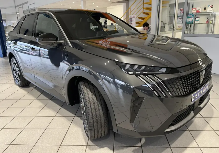 Peugeot 3008 gris titanium en 3/4 avant droit, avec calandre noire et feux LED griffés, en showroom.