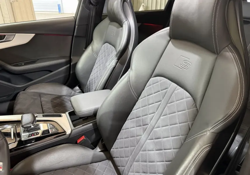 Vue intérieure rapprochée des sièges avant en cuir noir et tissu gris avec logo S embossé sur un Audi A4 35 TFSI 2022.