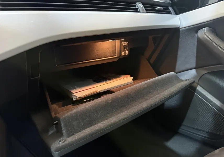 Gant de boîte à gants ouvert côté passager avec manuel Audi dans l’habitacle gris foncé d’une Audi A4 35 TFSI 2022.