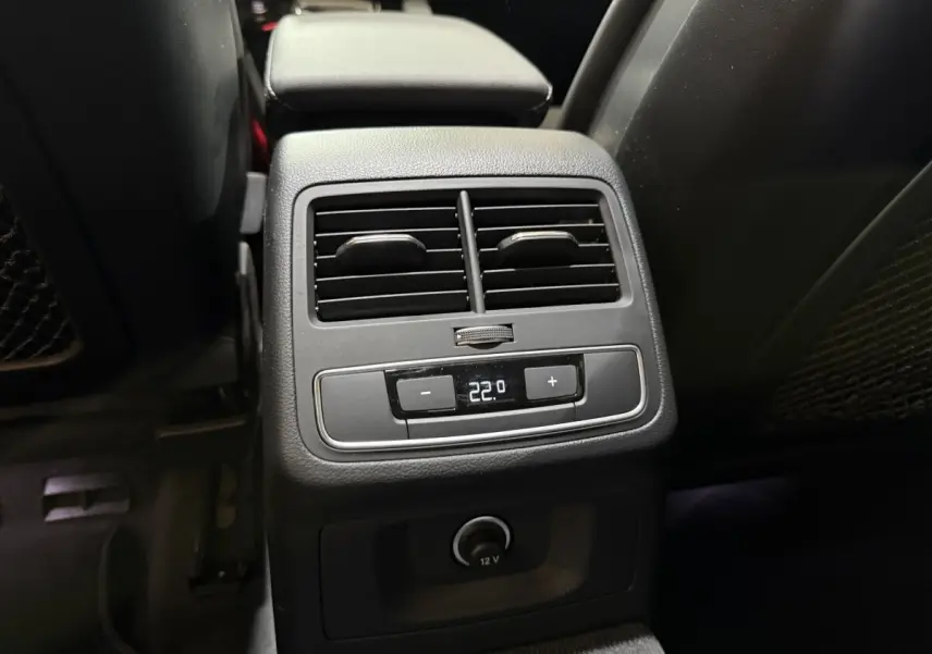 Vue rapprochée de la console arrière noire avec commandes climatisation et prise 12V dans l’Audi A4 gris foncé 2022.