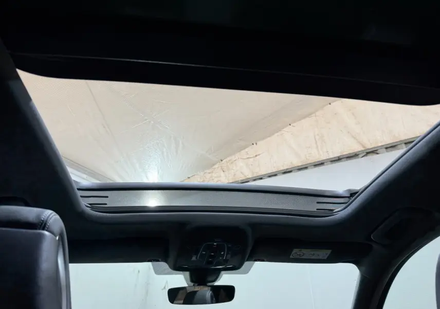 Vue intérieure du toit ouvrant panoramique de l'Audi A4 gris foncé, avec commandes intégrées au plafond.