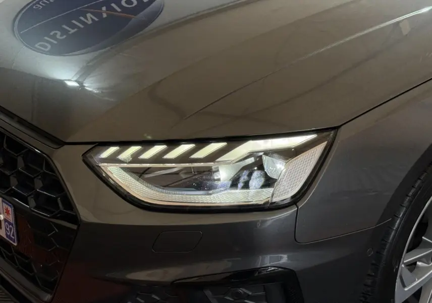 Gros plan sur le phare avant droit et la calandre d’une Audi A4 gris foncé 35 TFSI 2022, détails LED visibles.