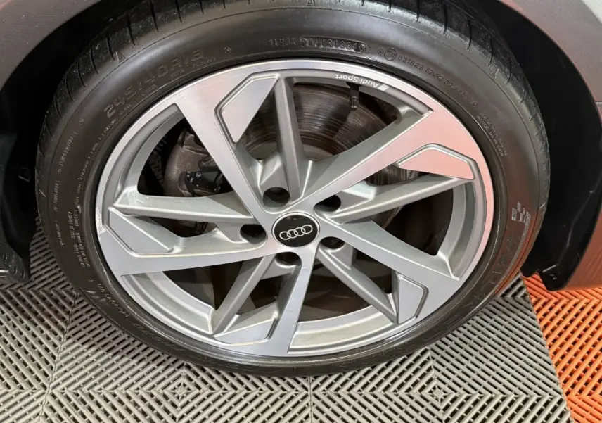 Gros plan sur la jante alliage argentée Audi Sport d’une Audi A4 gris foncé, vue côté droit.