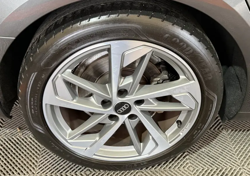 Gros plan sur la jante alliage argentée Audi Sport et pneu Goodyear d'une Audi A4 gris foncé, roue arrière droite.