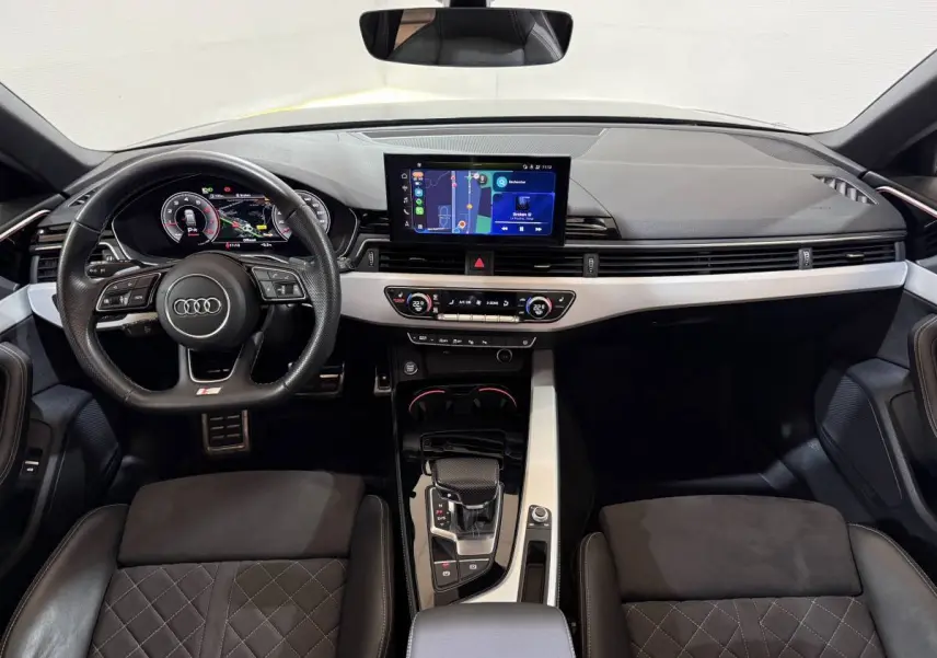 Vue intérieure avant de l'Audi A4 35 TFSI S Edition 2022, tableau de bord noir avec écran tactile central et volant cuir multifonctions.