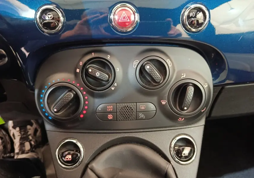 Vue rapprochée du tableau de bord bleu de la Fiat 500 Dolcevita 2022, montrant les commandes de climatisation et boutons centraux.