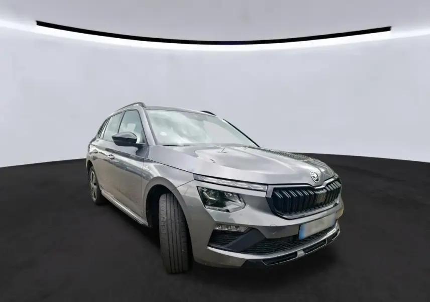 Vue 3/4 avant gauche d’un Skoda Kamiq gris foncé 2024 avec calandre noire et phares LED distinctifs.