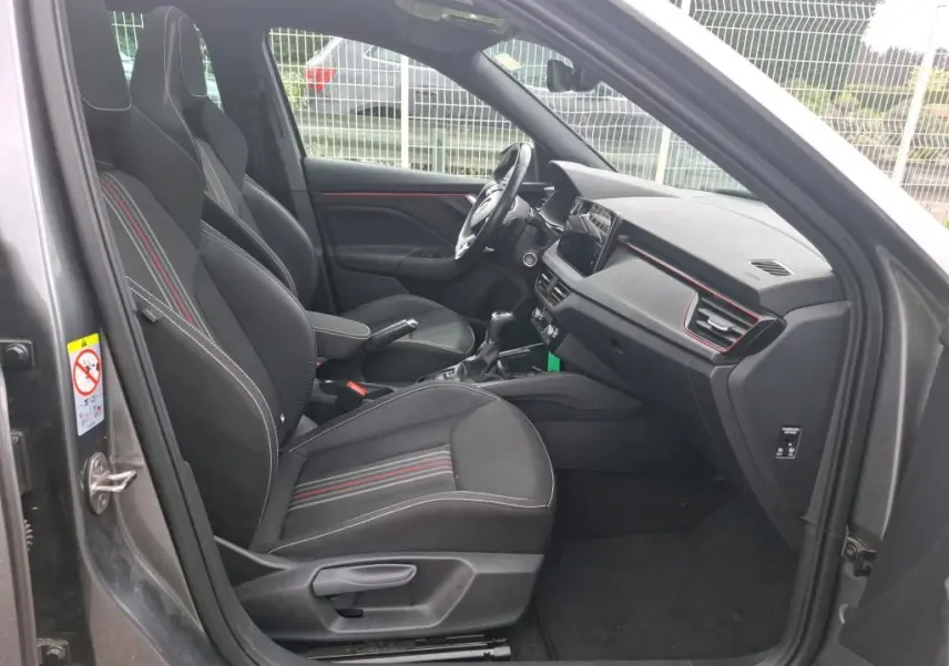 Vue intérieure côté conducteur du Skoda Kamiq gris foncé 2024, sièges tissu noir avec surpiqûres rouges et tableau de bord moderne.