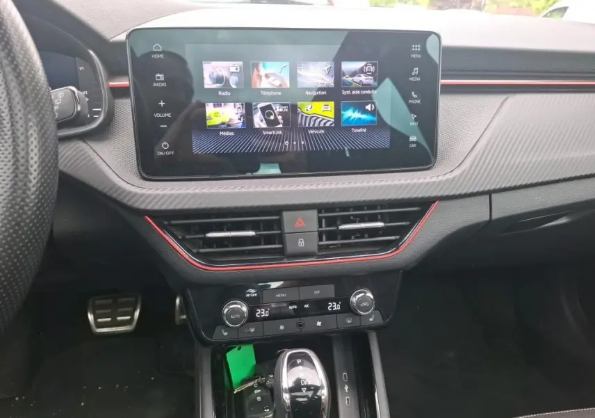 Vue intérieure centrée sur la console centrale du Skoda Kamiq gris foncé, avec écran tactile et commandes climatisation visibles.