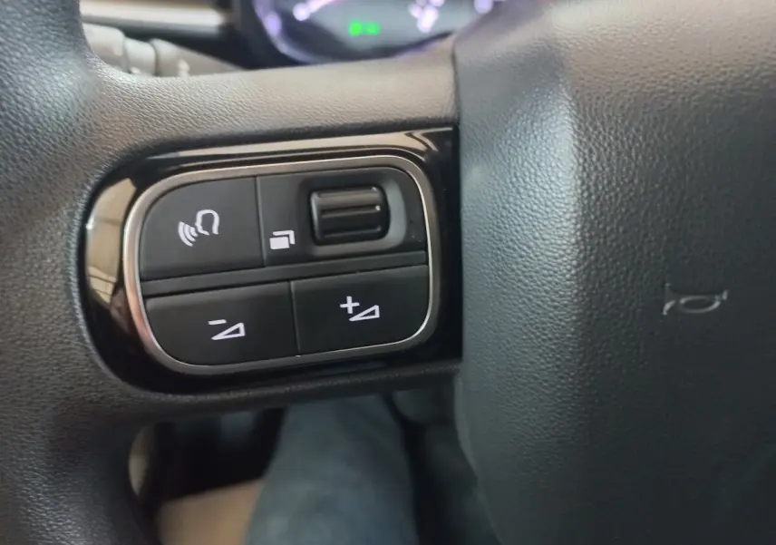 Gros plan sur les commandes gauche du volant multifonctions noir de la Citroën C3 BlueHDi 2024.