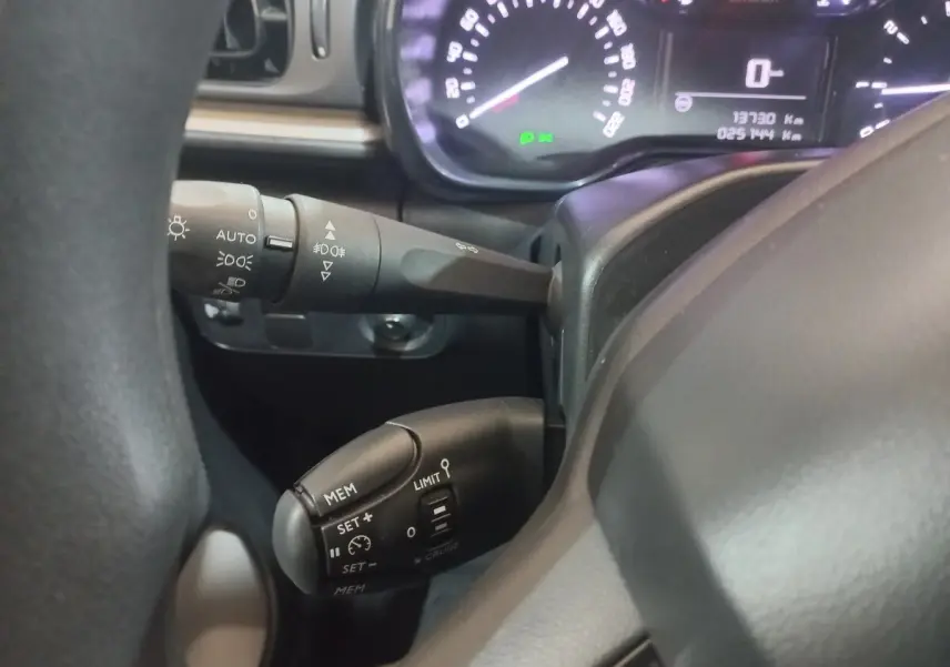Gros plan sur le volant noir de la Citroën C3 2024, montrant les commandes de régulateur de vitesse et les leviers de clignotants.