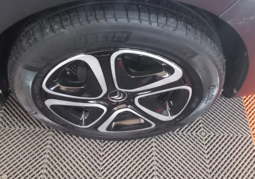 Gros plan sur la roue avant droite noire d'une Citroën C3 2024 avec jante alliage au design moderne bicolore.