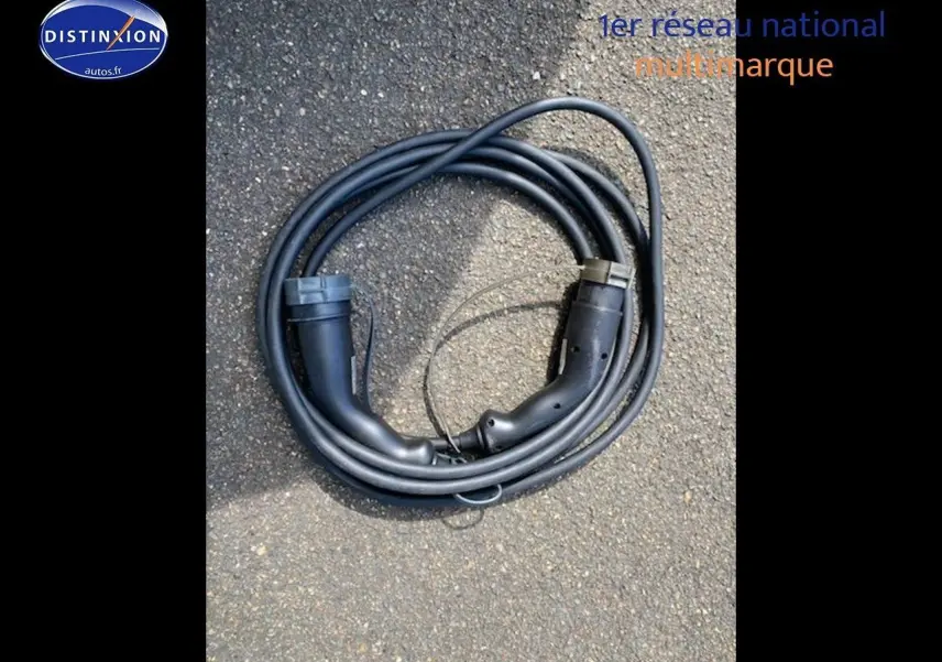 Câble de recharge noir pour Nissan Leaf électrique 40kWh Acenta posé sur sol bitumé, sans véhicule visible.