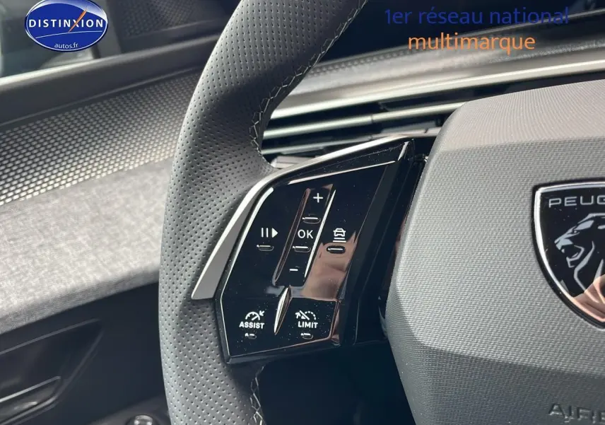 Gros plan sur le volant cuir perforé du Peugeot 3008 Hybrid 145 GT bleu obsession, avec commandes multifonctions visibles.