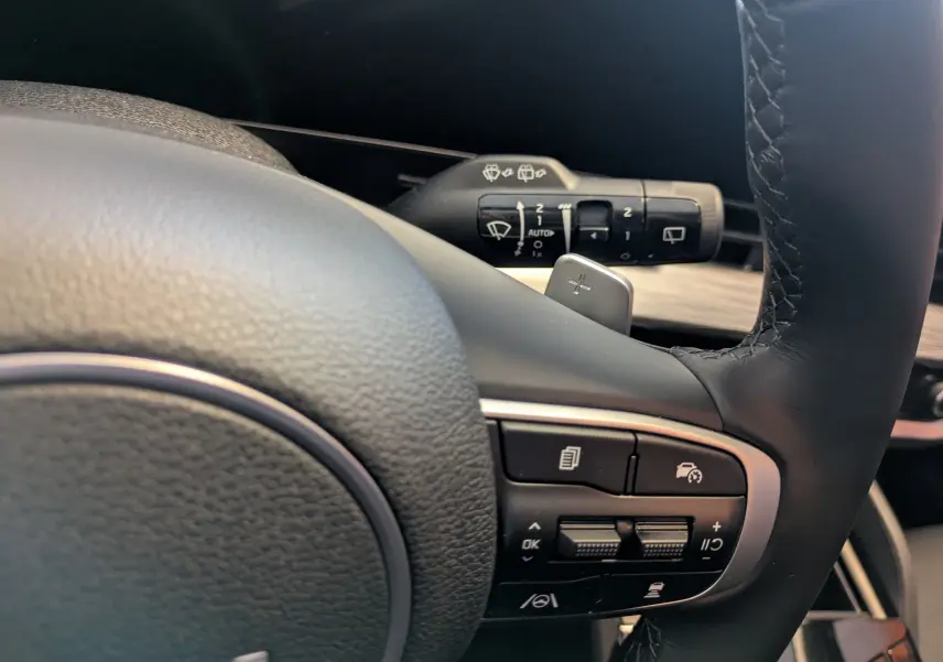 Gros plan sur le volant cuir du Kia Sportage MY25 avec commandes de régulateur et palettes au volant.