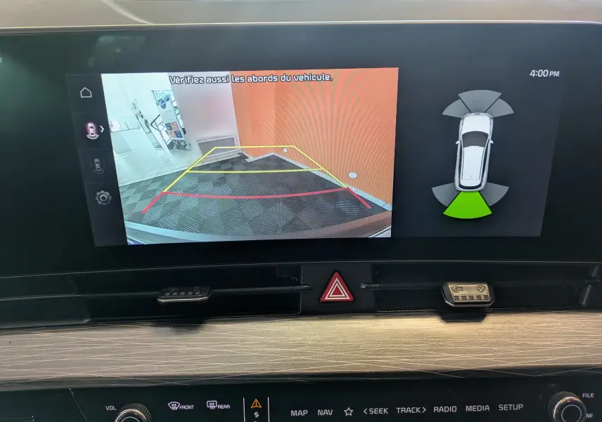 Écran tactile du Kia Sportage MY25 montrant la caméra de recul et l'alerte de proximité arrière en intérieur noir.