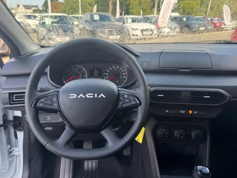 Vue intérieure frontale du volant DACIA et tableau de bord noir de la Sandero blanche Essential 2024