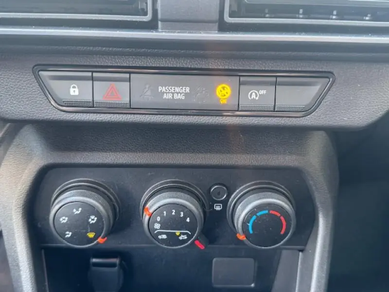 Vue rapprochée des commandes de climatisation et des voyants du tableau de bord d'une Dacia Sandero blanche 2024.